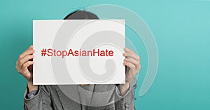 Stop asian hate write in white board paper.Asian Woman holding paper on green mint or Tiffany Blue background photo