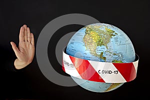 Stop the coronavirus. Hand imposes stop to spread of coronavirus, COVID-19. Planet earth with caution barrier tapes. In the