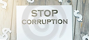 Stop Corruption Words on page and paper dollar signs around on wooden table. Anticorruption business concept photo