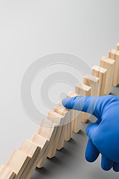 Stop COVID-19. A hand in a blue medical glove stops the domino effect. Preventive measures to combat the global spread