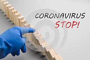 Stop COVID-19. A hand in a blue medical glove stops the domino effect. Preventive measures to combat the global spread
