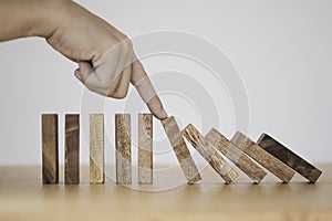 Stop crisis and risk management concept , Man using finger to stop wooden domino which falling to one wooden block still standing