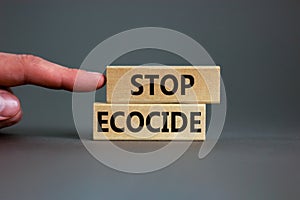 Stop ecocide symbol. Wooden blocks with words stop ecocide. Businessman hand. Beautiful grey background, copy space. Business,