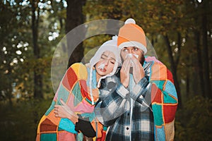 Stop the flu epidemy. Sick couple at cold forest wrapped in blankets sneeze and cough. Couple catch a cold and blow