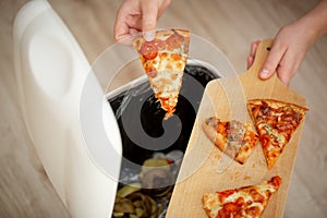 Stop food waste, young woman throwing leftover food into a trash can, food concept photo