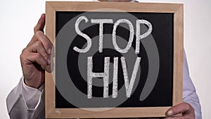 Stop HIV text on blackboard in doctor hands, AIDS awareness, disease prevention photo