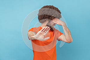 Stop, I don't want to see at this. Portrait Man covering his face and showing stop hand gesture.