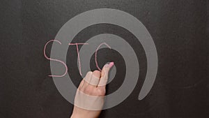 Stop! A left female hand writes the word `Stop!` by red chalk on a black board. Conceptual chalk drawing