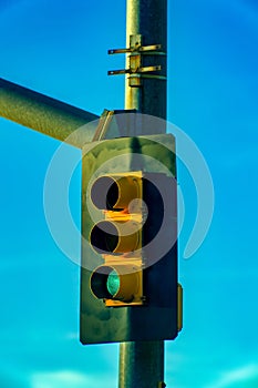 Stop light or traffic light with green selected in the afternoon sun with clear blue sky background