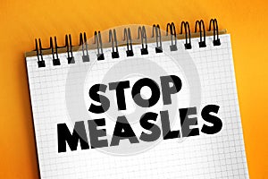 Stop Measles - get the measles, mumps, and rubella MMR vaccine, text concept on notepad