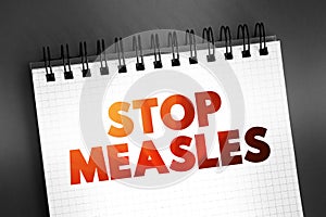 Stop Measles - get the measles, mumps, and rubella (MMR) vaccine, text on notepad, concept background