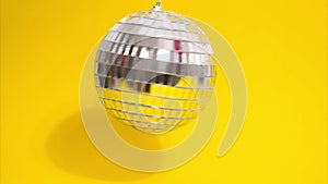 Stop motion animation of a disco ball moving on a yellow background