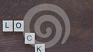 Stop motion animation with lettering lockdown, light wooden letters on a dark wooden background