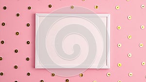 Stop motion animation mockup of white frame and gold colored push pins pattern around it on pink background. Flat lay top view.