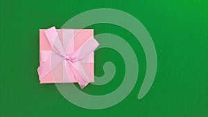 Stop motion animation of a pink gift box moving on a green chromakey background. Copy space
