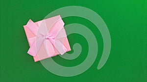 Stop motion animation of a pink gift box moving on a green chromakey background. Copy space