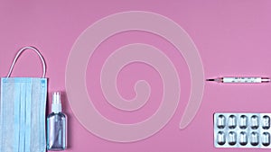 Stop motion animation of protective medicine mask, thermometer and pills on pink background, flat lay