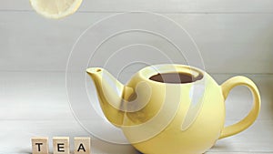 Stop-motion animation of tea preparation: water, lemon, tea bag added to the kettle and the sign tea neer the kettle