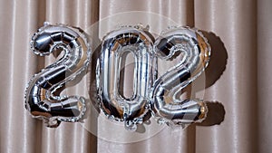 Stop motion Happy new year 2023 metallic balloons on atlas textile background. Greeting card silver foil balloons