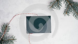 Stop motion video of green opening envelope on white background with branches of Christmas tree. Copy space