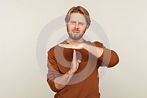 Stop, need pause! Portrait of disgruntled man with beard wearing sweatshirt doing time out gesture, demanding break