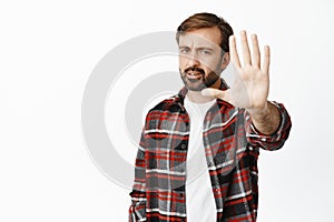 Stop it, no photos. Serious and disappointed bearded man extending palm in taboo gesture, prohibit something, rejecting