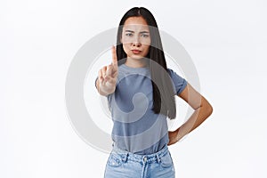 Stop right her. Silly asian girl pulling index finger forward in stop or prohibition motion, shake forefinger telling no