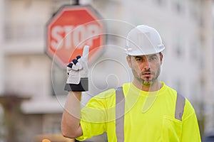 Stop road sign. Builder with stop gesture, no hand, dangerous on building concept. Man in helmet showing stop road sign