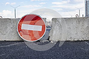 A stop road sign and concrete blocks block the entrance to the construction site. Closed road. Construction and road works