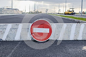 A stop road sign and concrete blocks block the entrance to the construction site. Closed road. Construction and road works