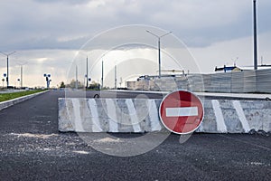 A stop road sign and concrete blocks block the entrance to the construction site. Closed road. Construction and road works