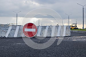 A stop road sign and concrete blocks block the entrance to the construction site. Closed road. Construction and road works