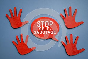 Stop self sabotage sign and wooden hands.