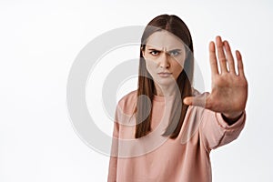 Stop it. Serious and determined woman extend palm and say no, forbid and disagree, condemn smth bad, forbid and reject