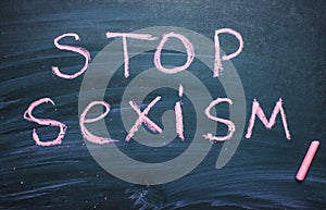 Stop sexism is written on a chalkboard chalk