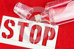 Stop sign, bottle and shot glass on the red tablecloth. The danger of alcoholism