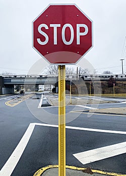 Stop sign by dangerous intersection with train tressel in background