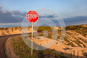 A stop sign on the edge of a cliff at Badlands National Park, at sunset time, South Dakota