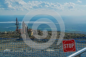 `Stop` sign on the fence in front of road equipment on the top of the mountain