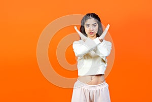 Stop sign with hands criss-cross. Frightened woman showing stop sign with hands on orange background