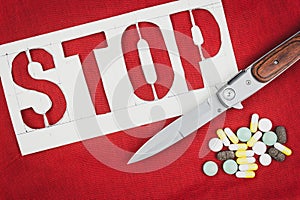 A stop sign, the knife and pills on red background. The risk of crime