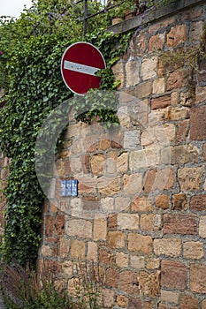 A stop sign on an old vintage stone castle wall overgrown with loach and plants