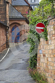 A stop sign on an old vintage stone castle wall overgrown with loach and plants with a blue castle door arch