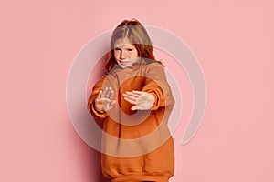 Stop sign. One scared little girl, kid with long red hair and freckles posing  over pink background. Concept of