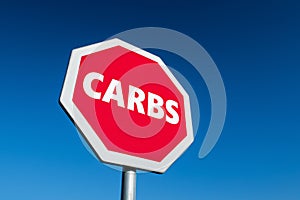 Stop sign in perspective view  with a text CARBS against blue sky to lose weight and live more healthy life and ketogenic diet