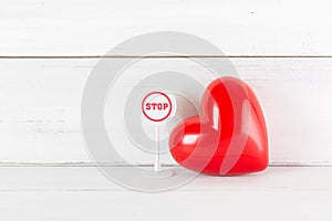Stop Sign with Read Heart on white wood background. Broken Love Concept with Copy Space