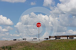 Stop sign, red circle and white text. Stop sign on an old rural road, cloudy blue sky background