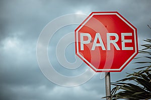 Stop sign in Spanish pare sign under a cloudy sky photo