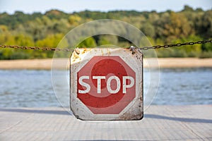 Stop sign on suspended chain. Road sign to warn to stop. Background with nature and vegetation