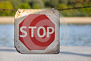 Stop sign on suspended chain. Road sign to warn to stop. Background with nature and vegetation